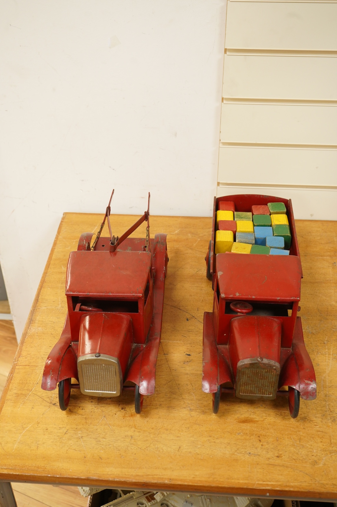 Two 1930's/40's Tri-ang large scale tinplate trucks, both with similar frames and cabs, one as a wreck truck with mounted crane, the other has a wagon with painted wooden blocks, each approximate 44cm long